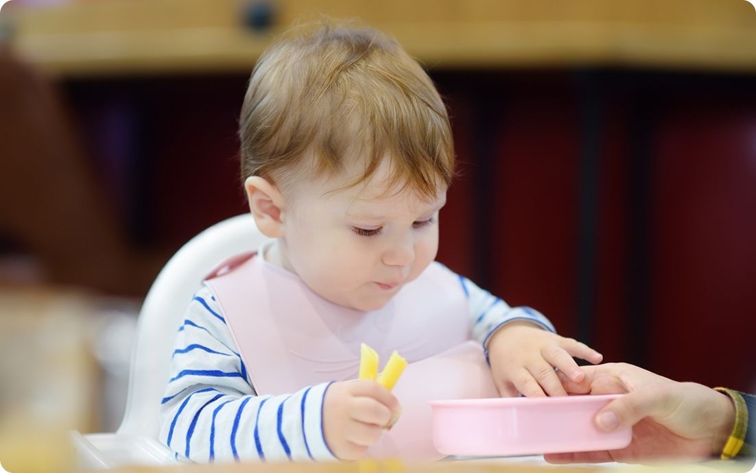 Baby eating food from a bowl.