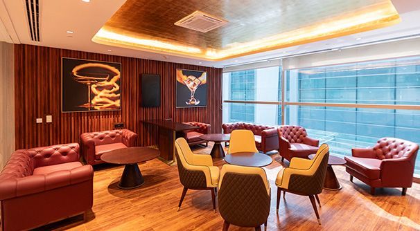 Interior of an airport lounge with seating, tables, and large windows