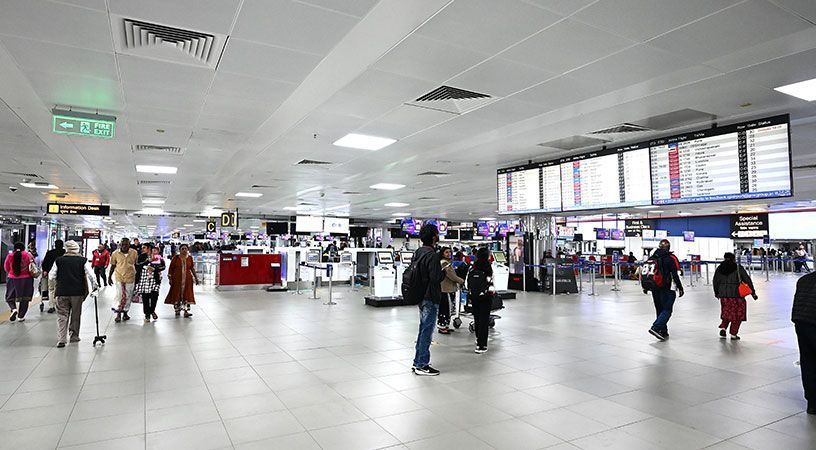 Airport terminal check-in hall with passengers and flight information displays